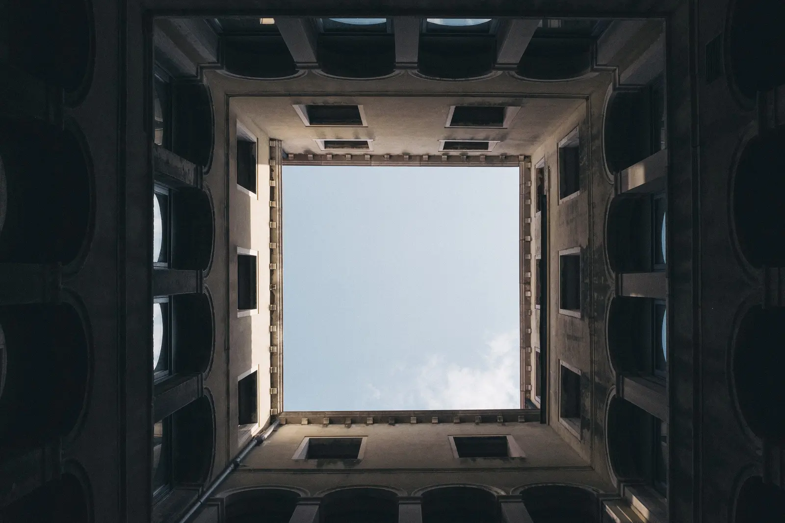 Looking straight up a rectangular light well to a bright sky.